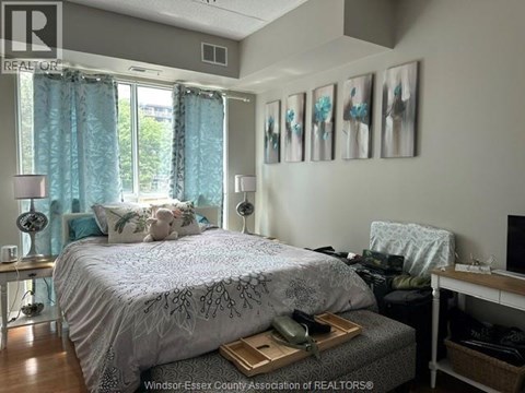 A bedroom with a bed, nightstand, and a window with curtains.