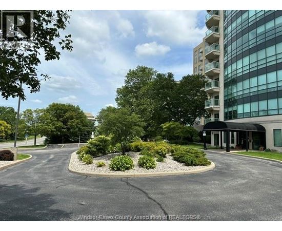 A parking lot with a building and trees in the background.