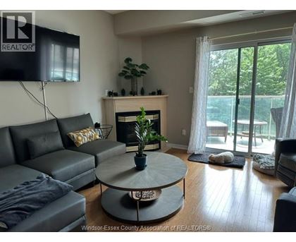 A living room with a grey couch and a fireplace.