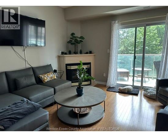 A living room with a grey couch and a fireplace.