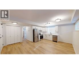 A spacious kitchen with wooden floors and white walls.