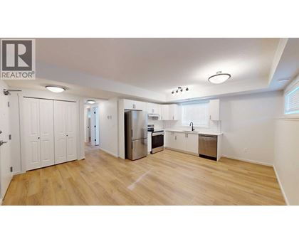 A spacious kitchen with wooden floors and white walls.