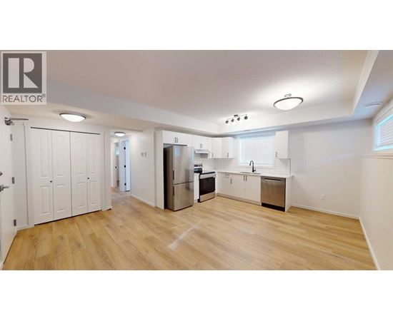 A spacious kitchen with wooden floors and white walls.