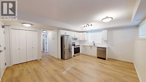 A spacious kitchen with wooden floors and white walls.
