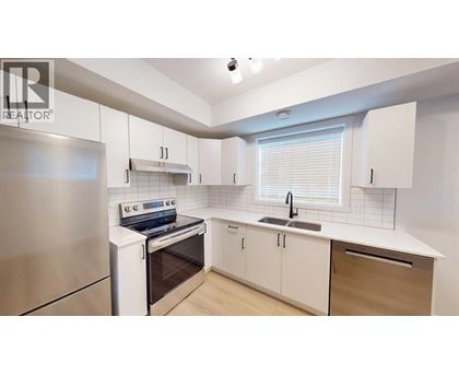 A modern kitchen with white cabinets and a stainless steel refrigerator.