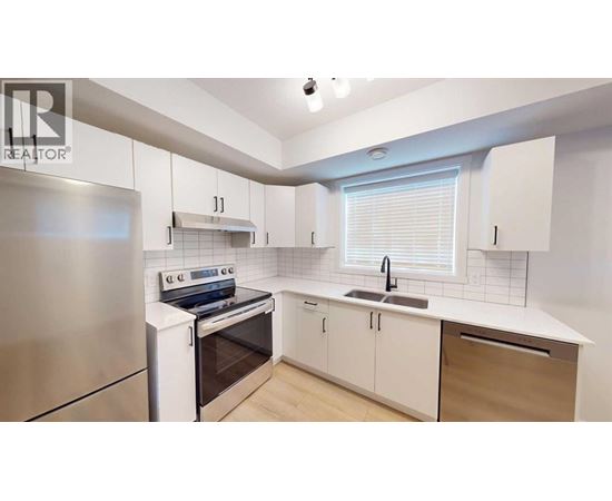A modern kitchen with white cabinets and a stainless steel refrigerator.