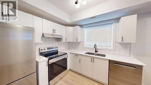 A modern kitchen with white cabinets and a stainless steel refrigerator.