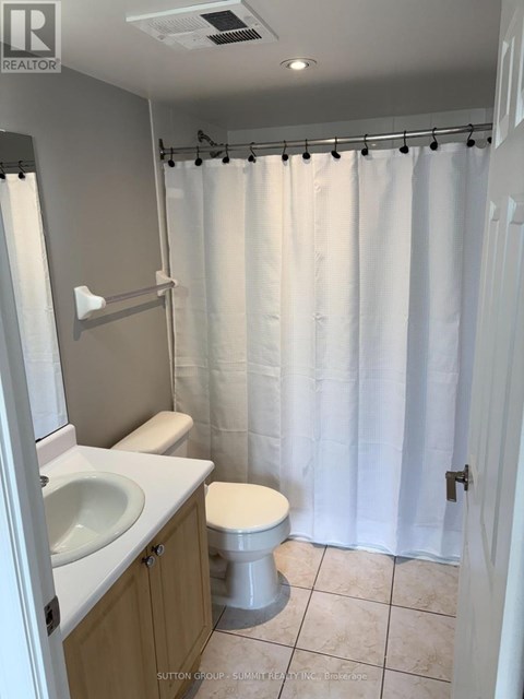 A white bathroom with a toilet, sink, and shower curtain.