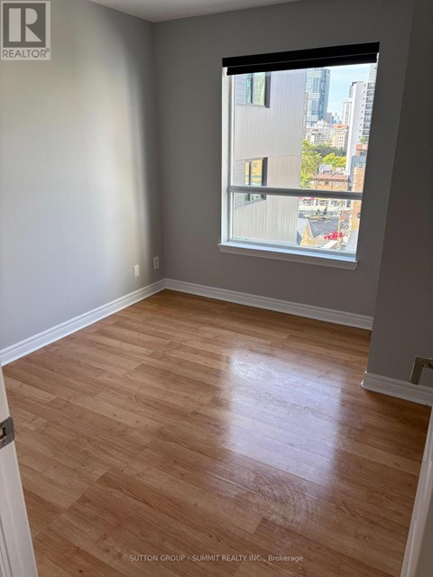A room with wooden flooring and a window showing a city view.