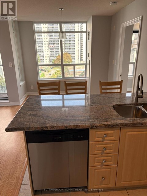 A kitchen with a dishwasher and wooden chairs.