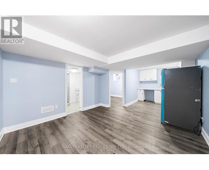A spacious room with wooden flooring and a large refrigerator.