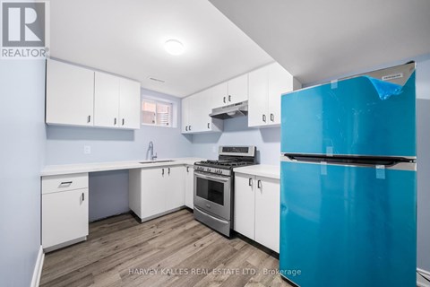 A kitchen with white cabinets and a blue fridge.