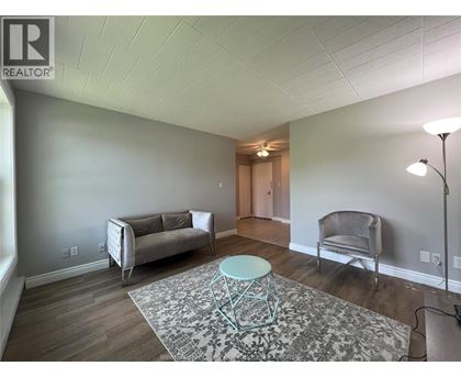 A living room with a grey couch, a chair, and a round table.