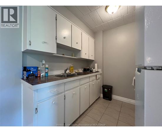A kitchen with white cabinets and a black trash can.