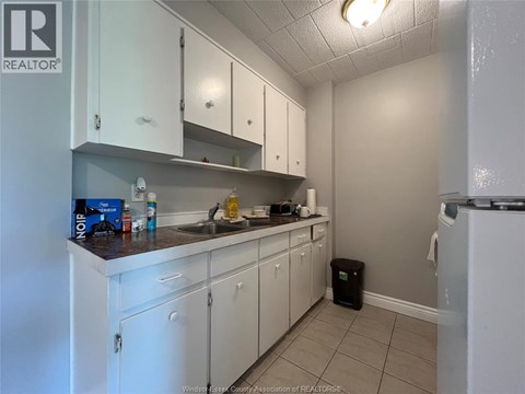A kitchen with white cabinets and a black trash can.