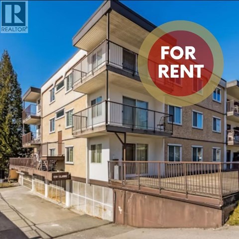 A multi-story apartment building with a balcony and a sign that says "FOR RENT".