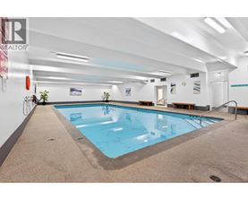 A large indoor swimming pool with a tiled floor and a white wall.