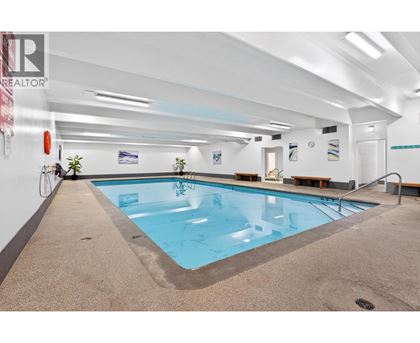 A large indoor swimming pool with a tiled floor and a white wall.
