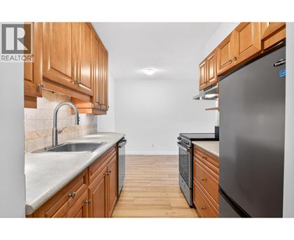 A kitchen with wooden cabinets and a stainless steel refrigerator.