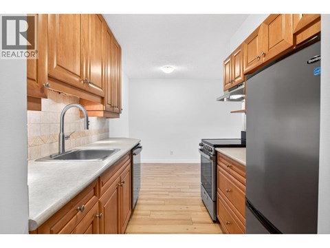 A kitchen with wooden cabinets and a stainless steel refrigerator.