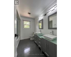 A bathroom with a toilet, sink, and mirror.