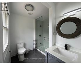 A white bathroom with a toilet, sink, and mirror.