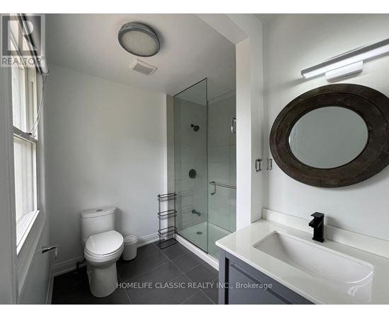 A white bathroom with a toilet, sink, and mirror.