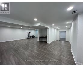 A spacious room with wooden flooring and white walls.