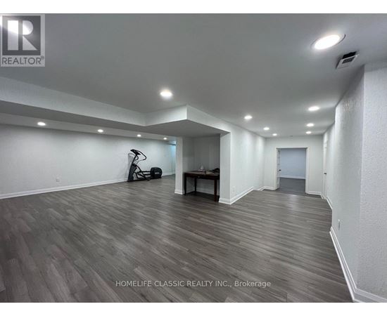 A spacious room with wooden flooring and white walls.