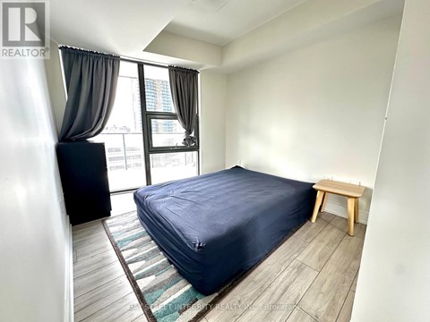 A bedroom with a bed, a bench, and a window with curtains.