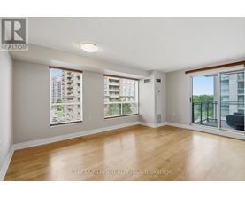 A spacious room with wooden flooring and large windows.