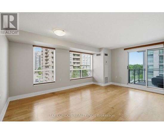 A spacious room with wooden flooring and large windows.