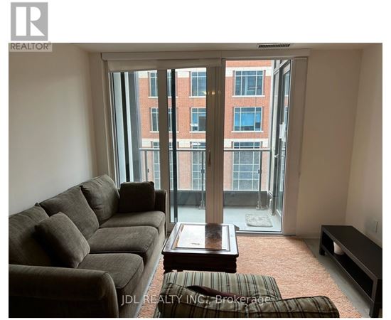 A living room with a couch, coffee table, and a view of a building through the window.