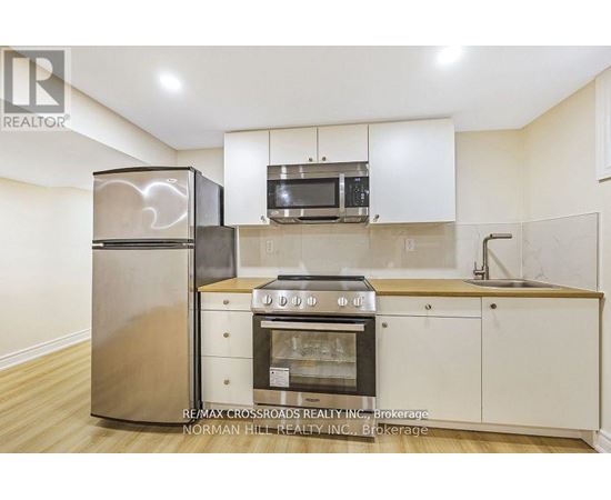 A kitchen with a refrigerator, microwave, oven, and sink.