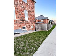 A red brick house with a wooden fence and a green lawn.