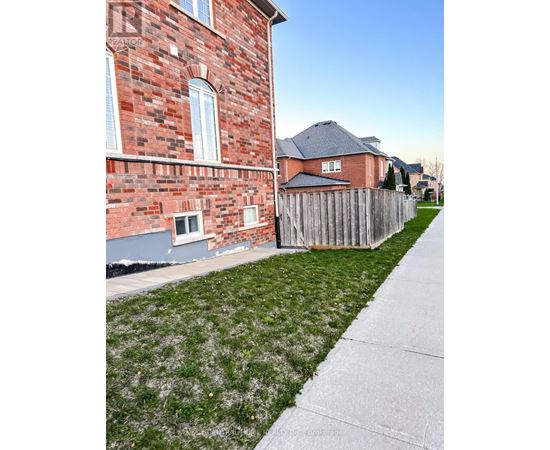 A red brick house with a wooden fence and a green lawn.