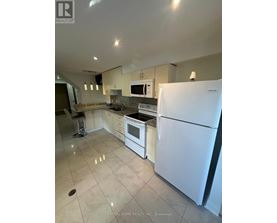 A white refrigerator stands in a kitchen with a countertop and stove.