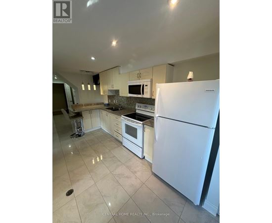 A white refrigerator stands in a kitchen with a countertop and stove.
