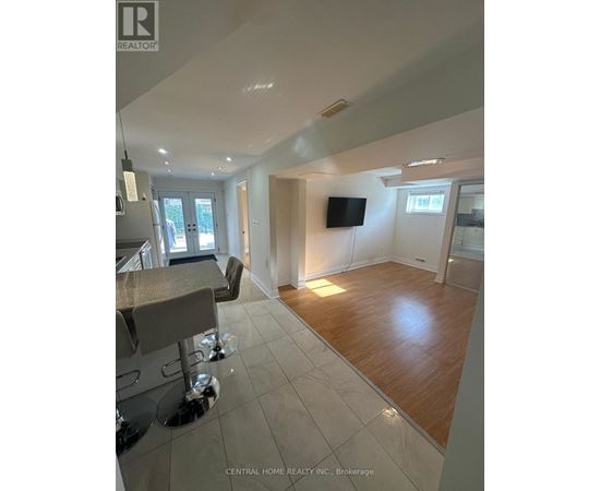 A spacious living room with a bar area and a television.