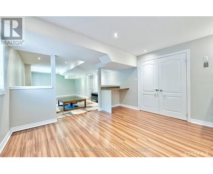 A spacious room with wooden flooring and white walls.