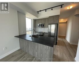 A modern kitchen with a black countertop and wooden cabinets.