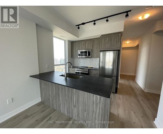 A modern kitchen with a black countertop and wooden cabinets.