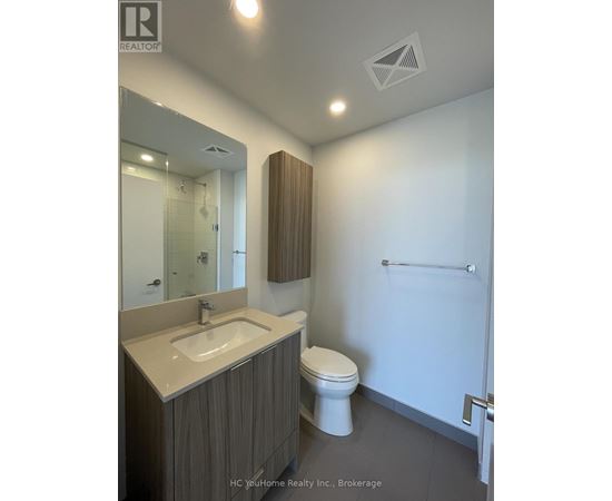 A bathroom with a toilet, sink, and mirror.