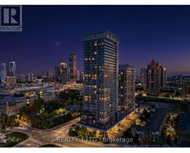 A nighttime cityscape with a tall building in the foreground and the REALTY 7 LTD. Brokerage logo in the bottom left corner.