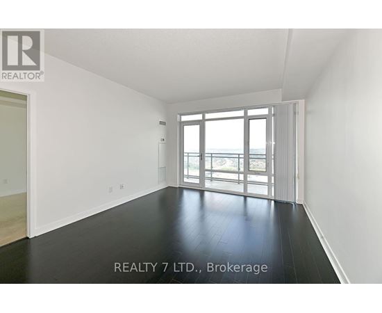 A spacious room with a sliding glass door leading to a balcony.