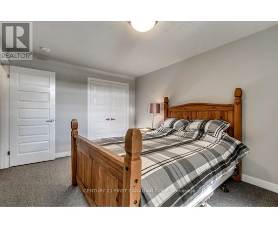 A bedroom with a bed, two doors, and a ceiling light.