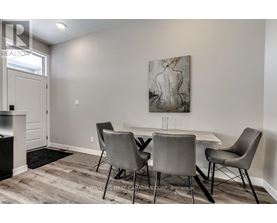 A dining room with a table and chairs and a painting on the wall.
