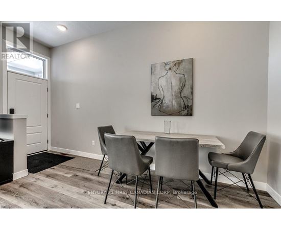 A dining room with a table and chairs and a painting on the wall.