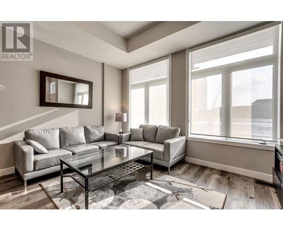A living room with a grey couch and a glass coffee table.