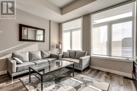 A living room with a grey couch and a glass coffee table.